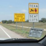 Texas windshield visibility laws and seat belt safety signage.
